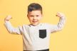 stockphotoimageoflittleboychildstandingisolatedoveryellowbackgroundlookingcamerashowingbiceps774844828.jpg