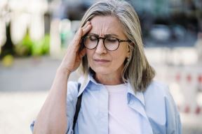 stockphotofeelinghardheadachemigrainematuregreyhairedwomanssstandingoutdoorsholdingher2195765533.jpg